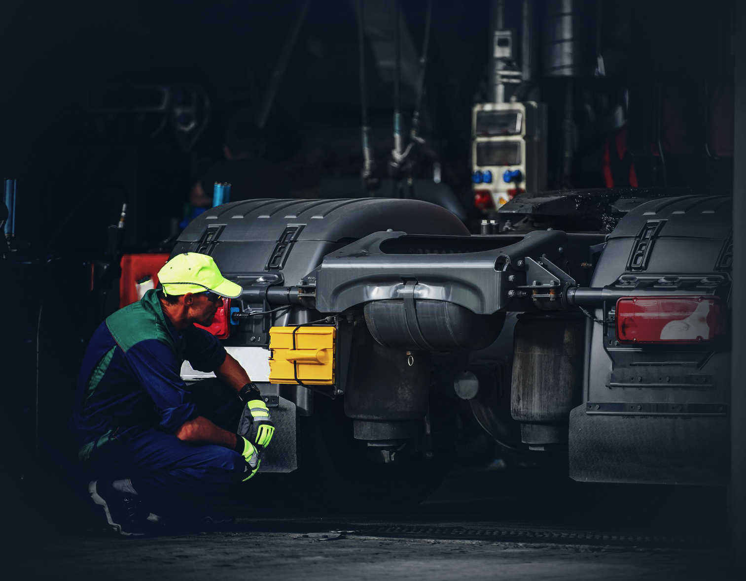 Ein Mechaniker in hochsichtbarer Arbeitskleidung führt Wartungsarbeiten an einem Nutzfahrzeug durch – typisch für die handwerkliche Expertise von Emil Steinebach GmbH, der Fachwerkstatt für Nutzfahrzeuge und Baumaschinen.